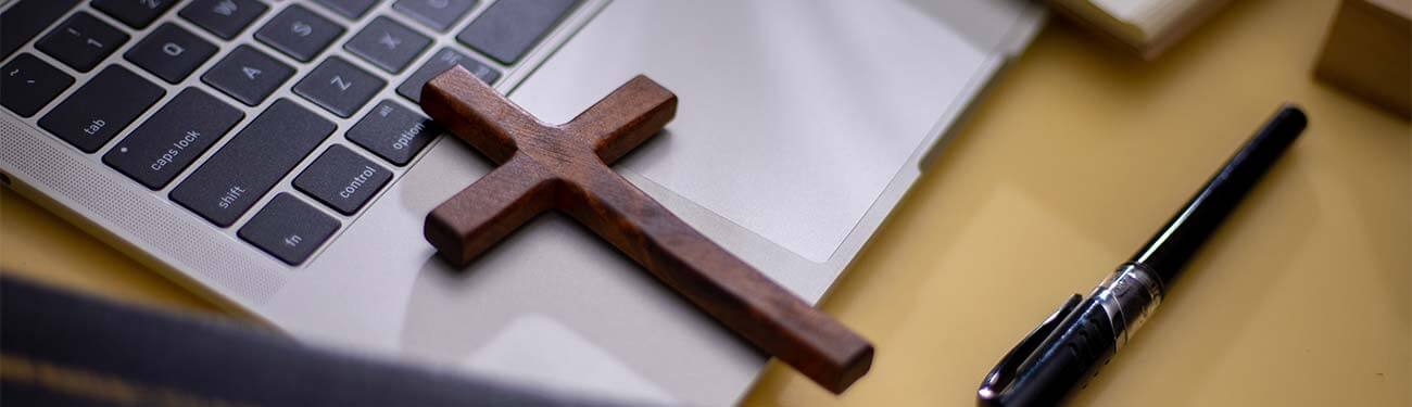 A wooden cross is sitting on top of a laptop keyboard.