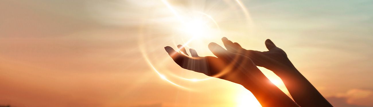 A person is reaching for the sun with their hands.