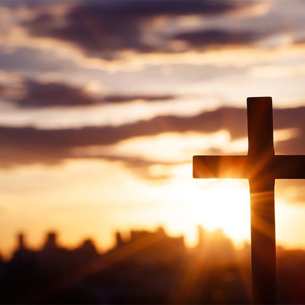 Silhouette of a cross against a glowing sunset sky