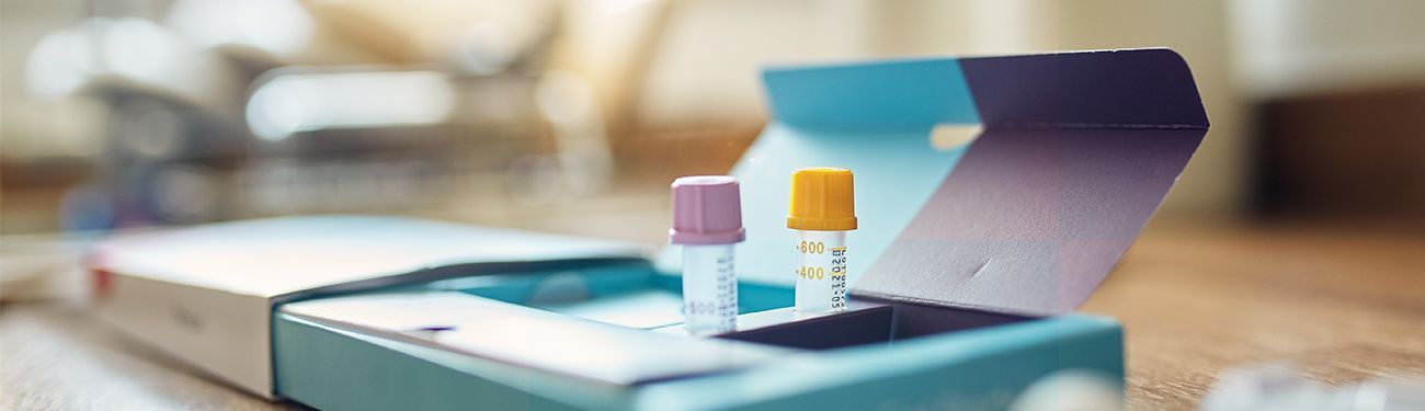 Two colorful DNA tubes in an open box on a wooden table. 