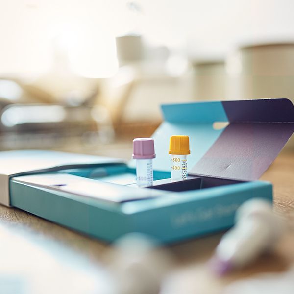 Open medicine box with two small vials on a wooden table, blurred background. 