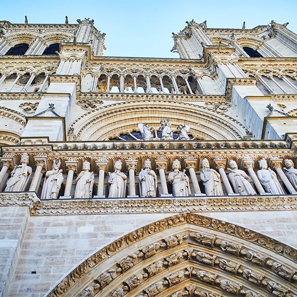 Ornate cathedral facade with statues, arches, and twin towers against a blue sky
