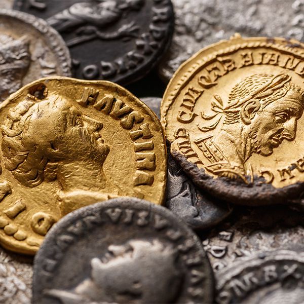Close-up of assorted ancient Roman-style coins in gold, silver, and dark metal tones.