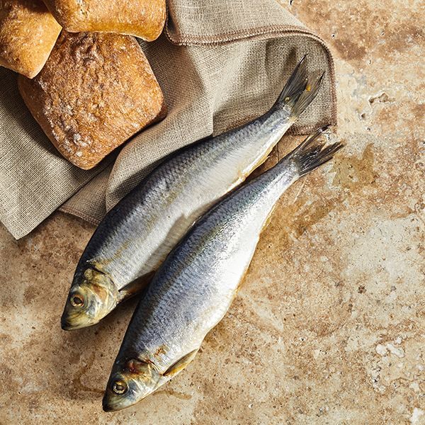 Two silver fish beside bread on a burlap cloth