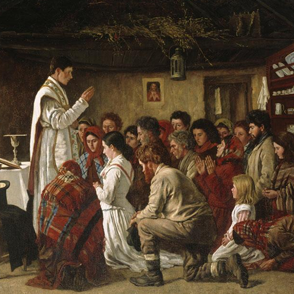 Priest in white robes addressing a seated group in a rustic thatched room