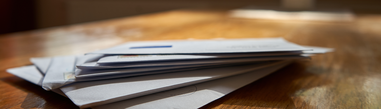A stack of white envelopes on a wooden table