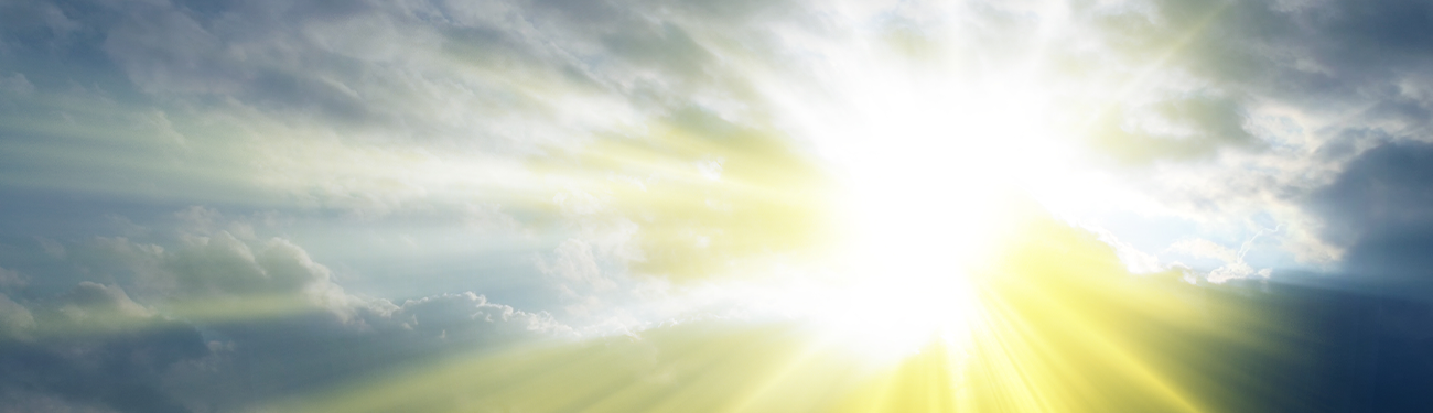 Bright sun breaking through clouds over a cloudy sky, with a yellow glow on the horizon.