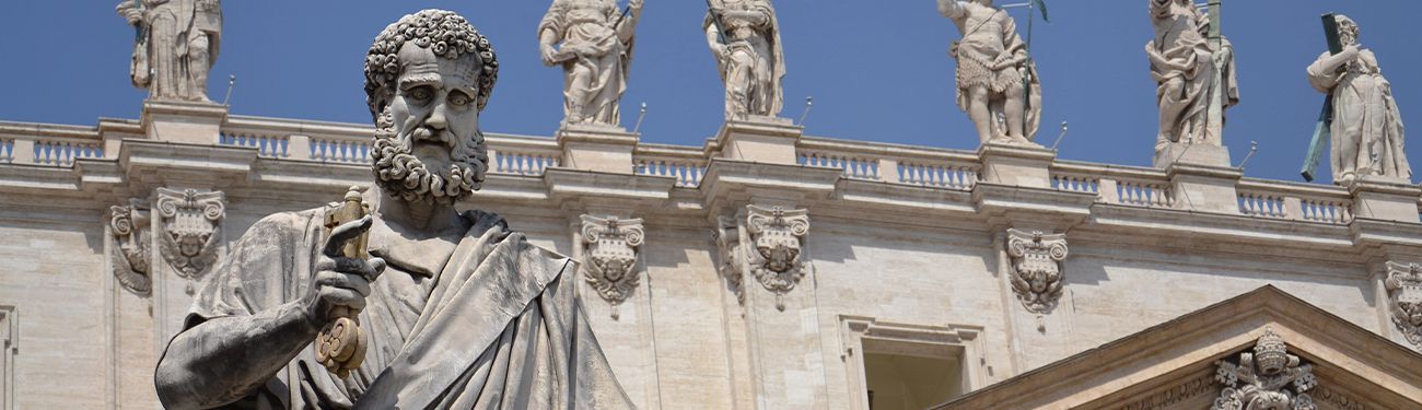 Statue in front of a classical stone building with ornate carvings and columns.