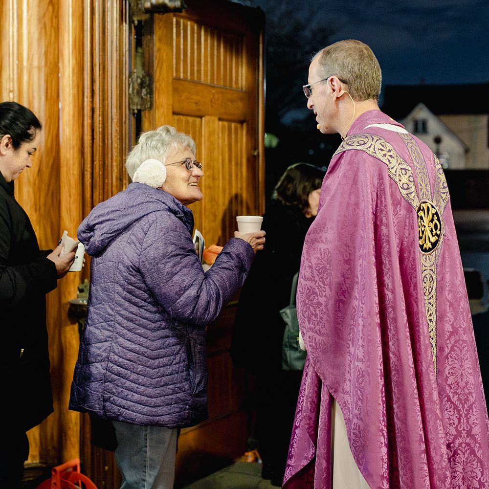 People gathered at a parish event talking to a priest.