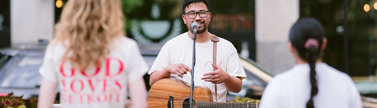 A man playing guitar at a church outreach event.