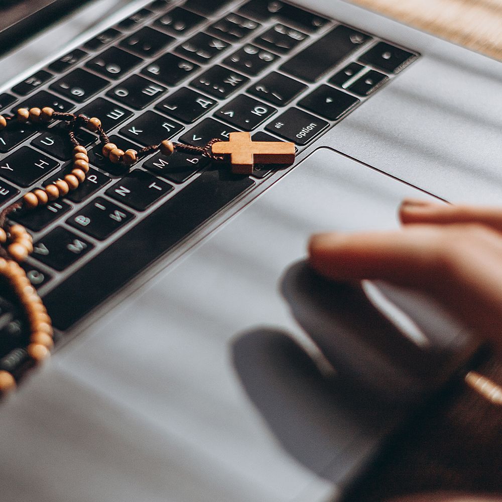 Computer keyboard with a rosary on top of it. 