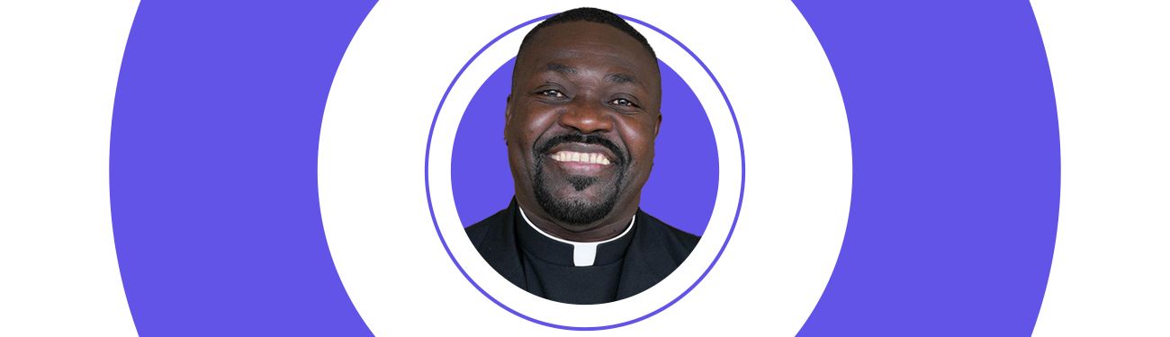 A Priest with a goatee is smiling in a purple and white circle.