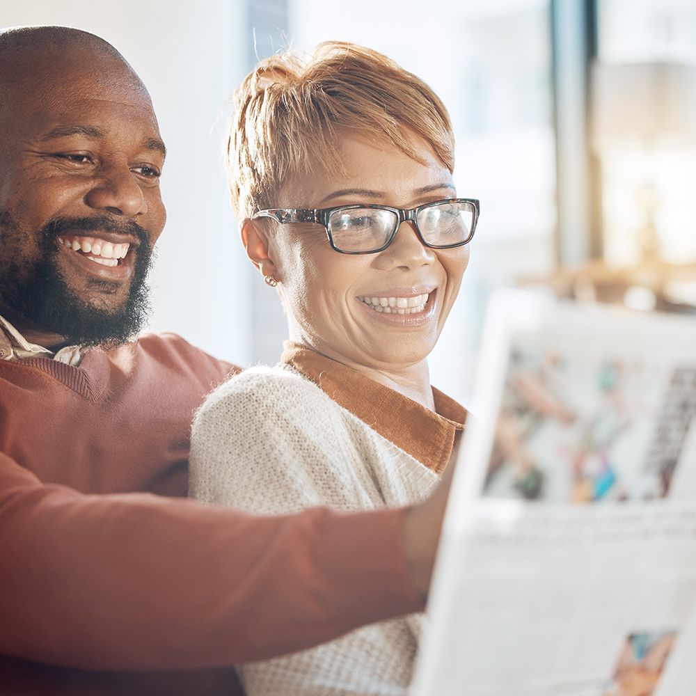 Two smiling people looking at a laptop together in a bright room