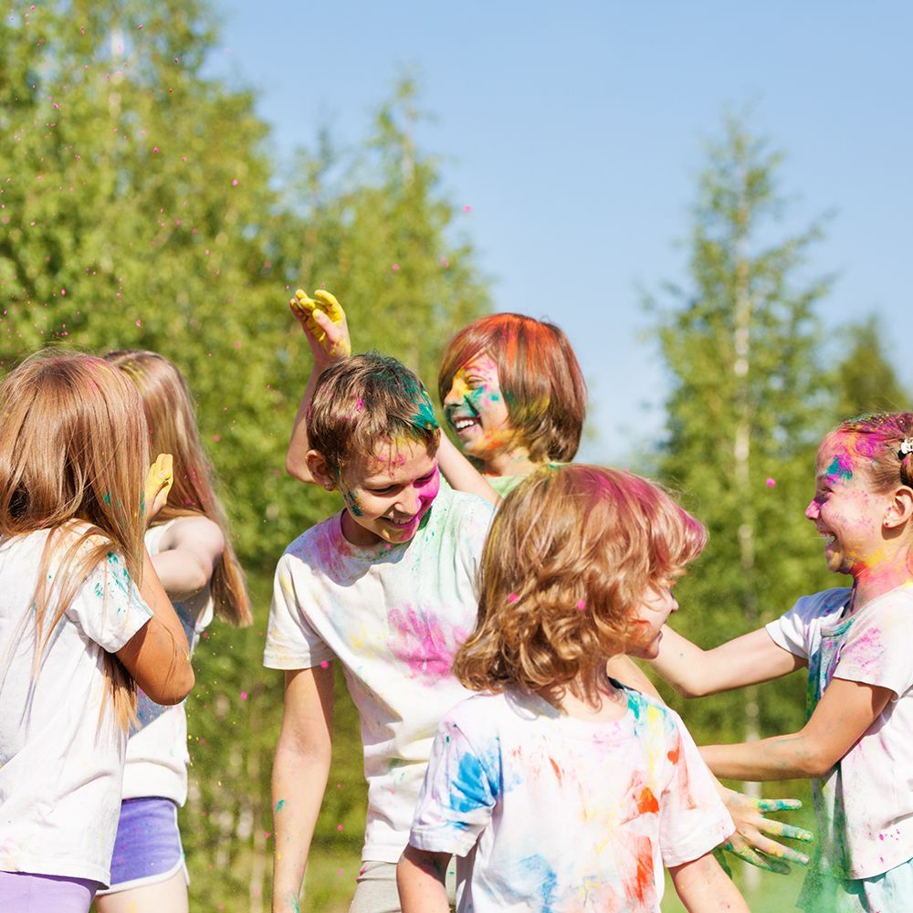 Children with colorful face paint laughing and playing outdoors at Vacation Bible School