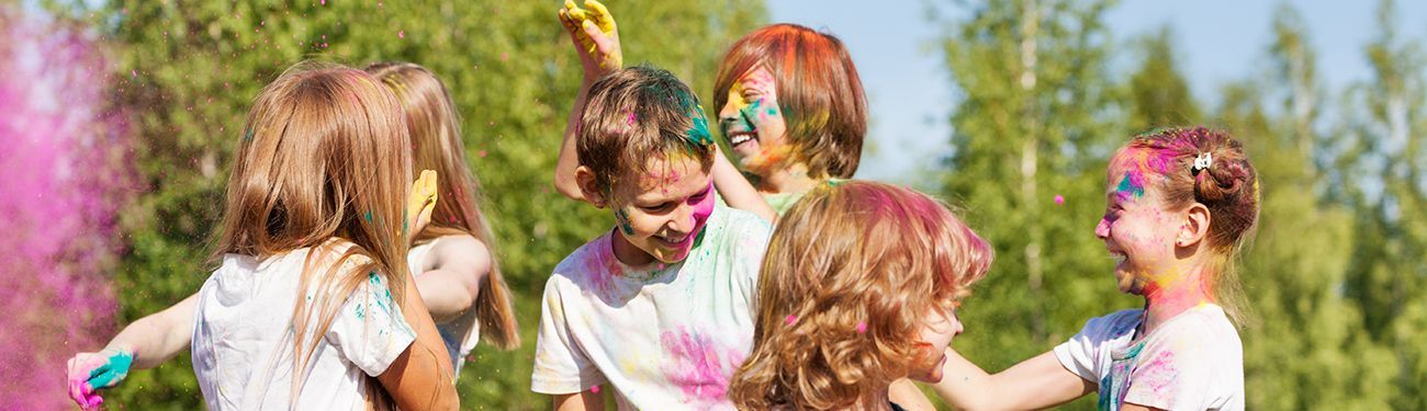 Children with colorful face paint laughing and playing outdoors at Vacation Bible School