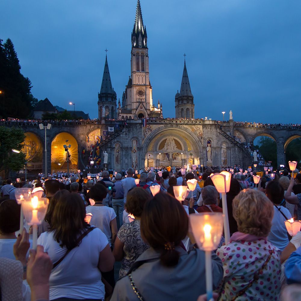 Catholics gathered outside of a church at night holding candles