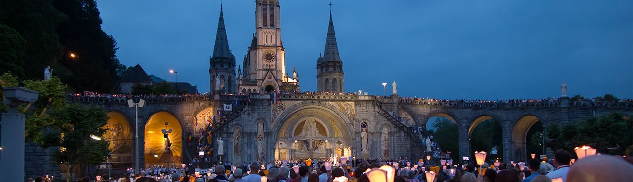 Catholics outside of a church in the evening holding candles