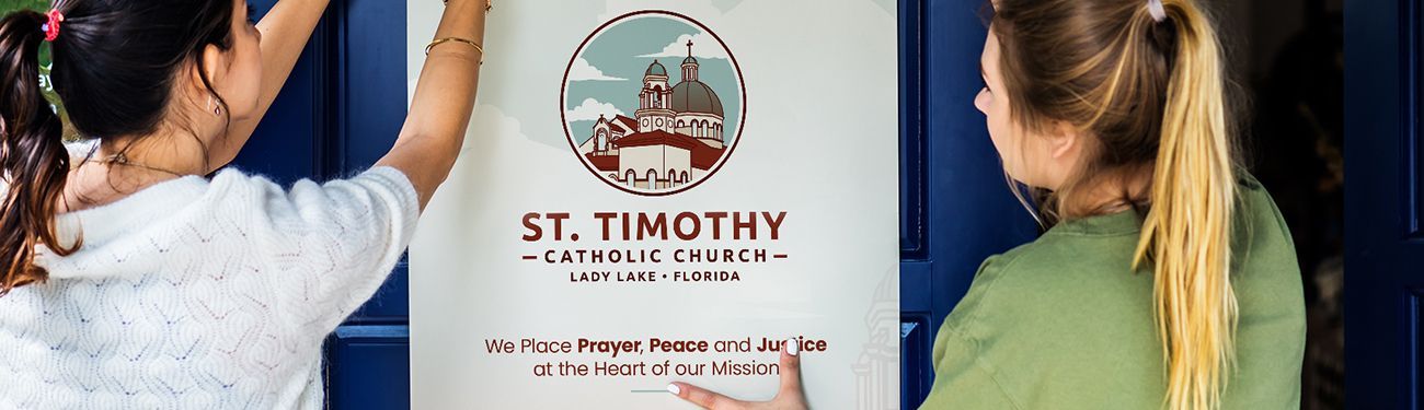 Two women are hanging a sign on a door for St. Timothy Catholic Church.
