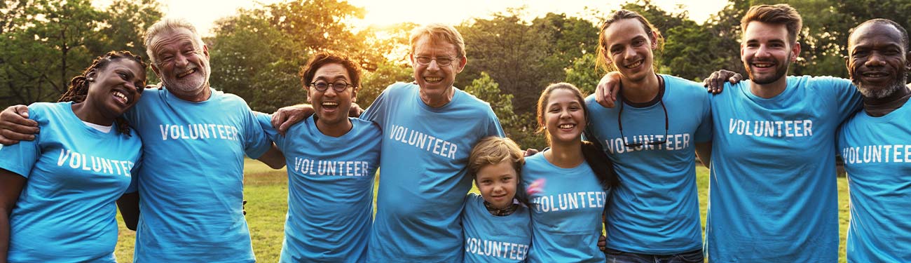 A group of volunteers are posing for a picture together in a field.