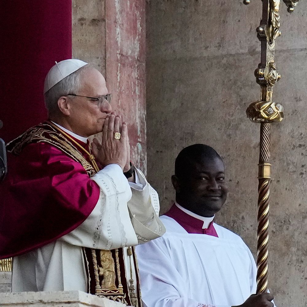 Pope in red vestments prays beside an altar server in white robes during a church ceremony