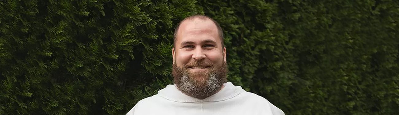 A man with a beard is wearing a white robe and smiling.