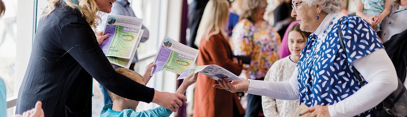 A child is handing a bulletin to a woman in a busy entrance way.