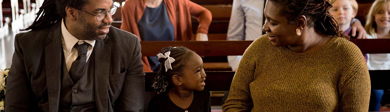 A families are sitting in a church smiling and talking.