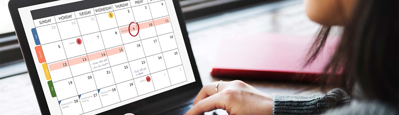 A woman is using a laptop computer with a calendar on the screen.
