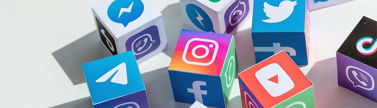 A bunch of cubes with social media icons on them are stacked on top of each other on a table.