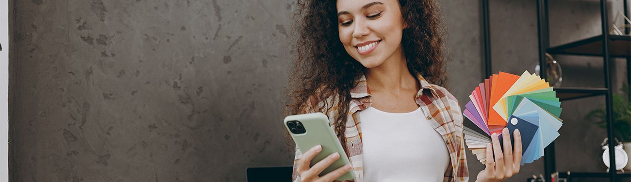 A woman is holding a cell phone while smiling.