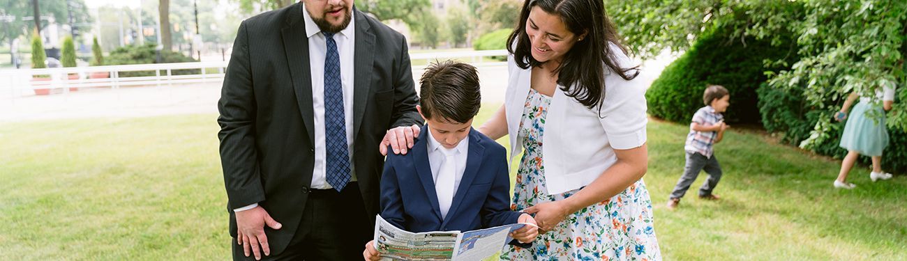 A family is standing in a park looking at a bulletin.