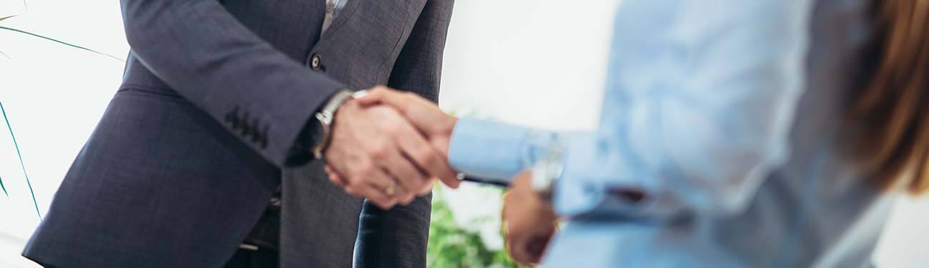 A man and a woman are shaking hands in an office.