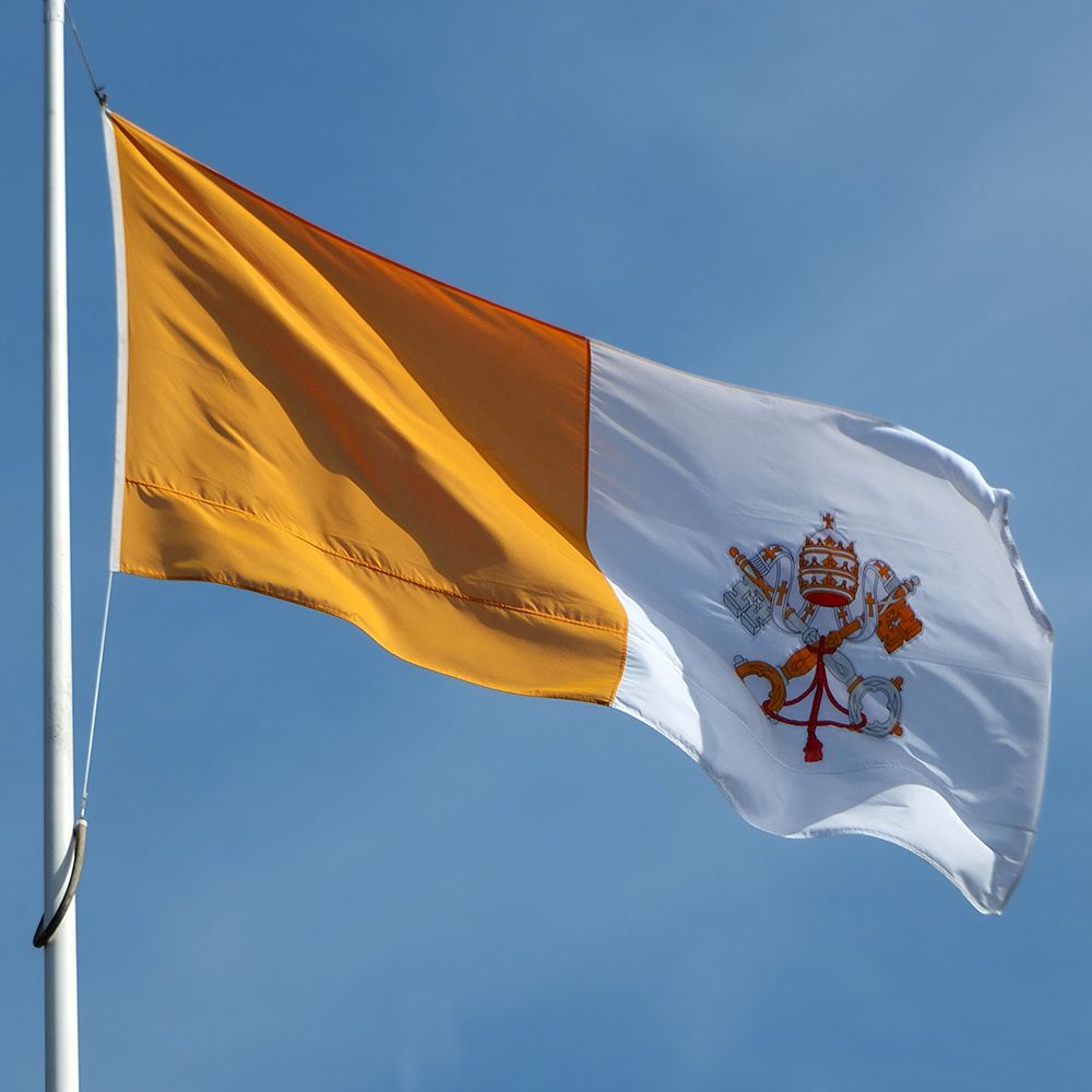 Photo of the Vatican flag flying against a blue sky.