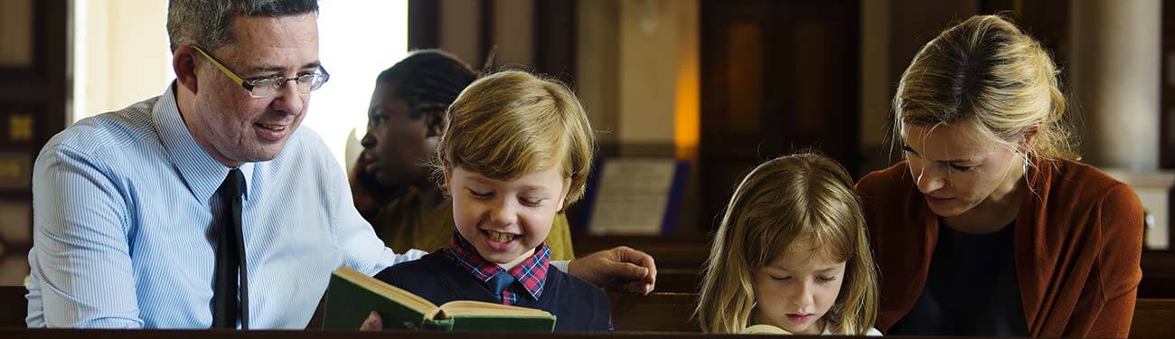 Five Letters That Will Invite School Families to Sunday Mass A father and son reading Bible in church.