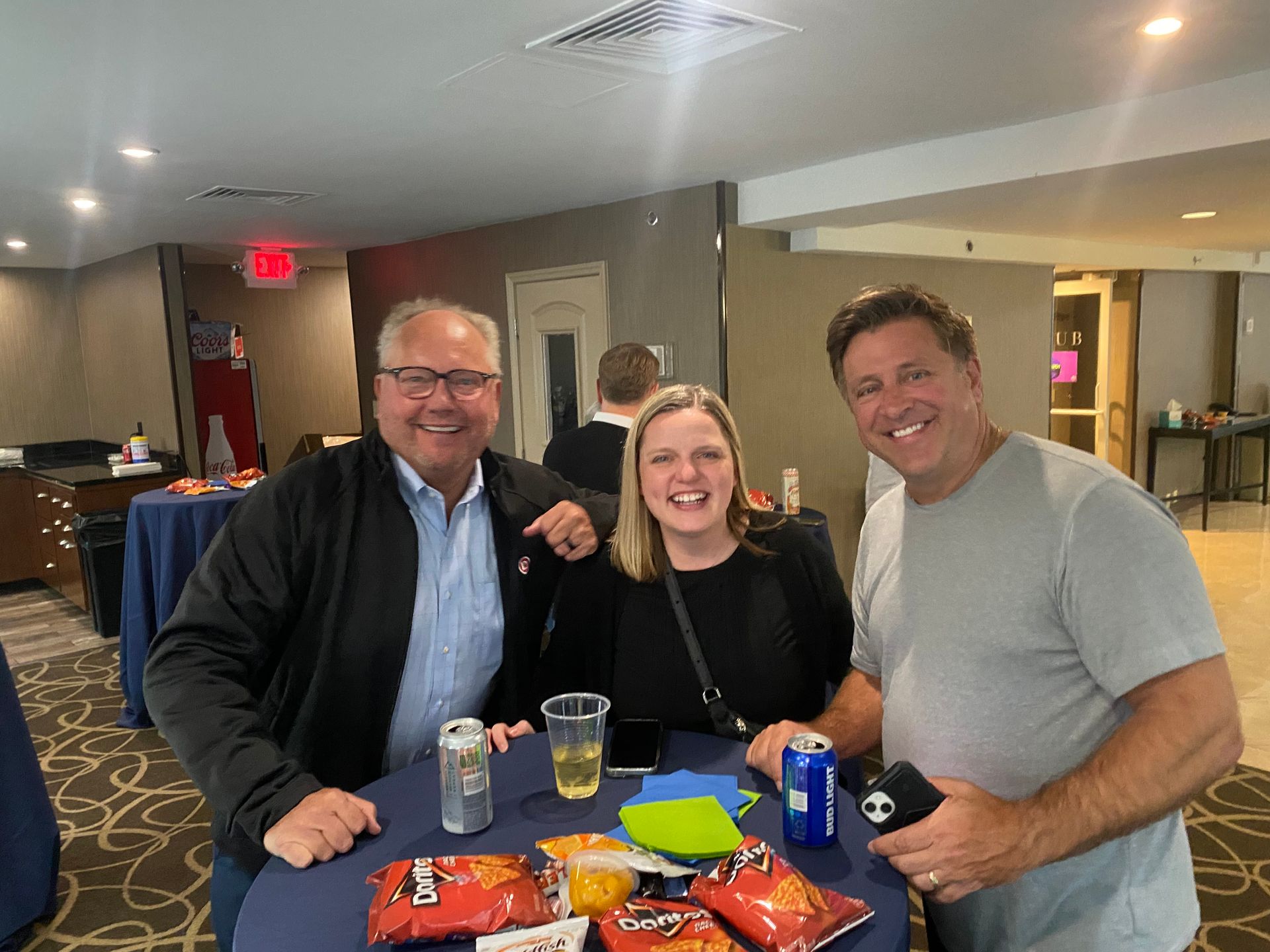 Two men and a women at a table smiling for the camera