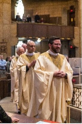 A group of Priests are walking through a church.