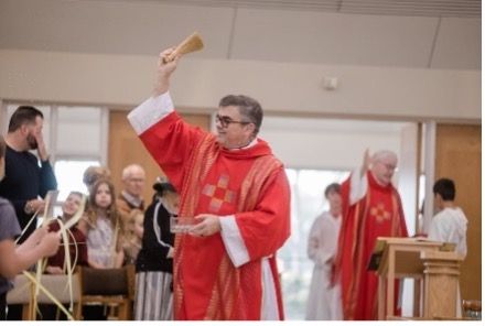 A man in a red robe is holding a wooden stick in his hand.