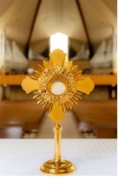 A gold monstrance is sitting on a table in a church.