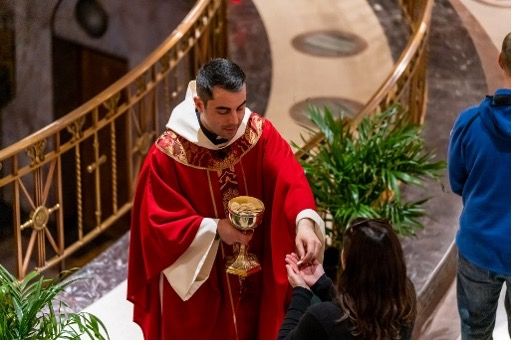 A Priest in a red robe giving communion.