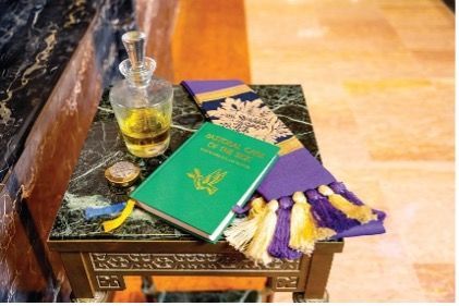 A green book is sitting on a table next to a bottle of oil.