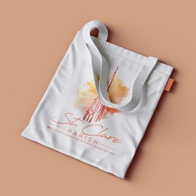 A white tote bag with a cross on it is sitting on a table.