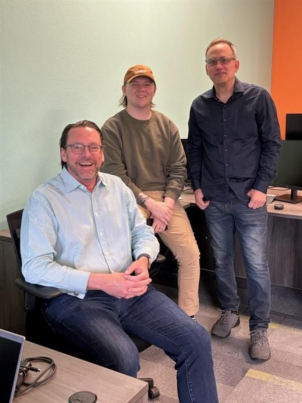 Three men are posing for a picture in an office.