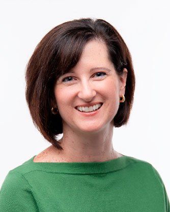 A woman in a green shirt is smiling for the camera.
