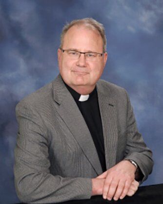 A man in a suit with a white collar is posing for a picture.