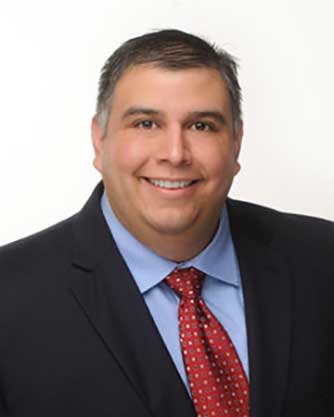 A man in a suit and tie is smiling for the camera.