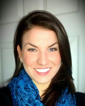 A woman wearing a blue scarf is smiling for the camera.