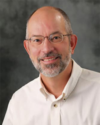 A man with a beard wearing glasses and a white shirt.