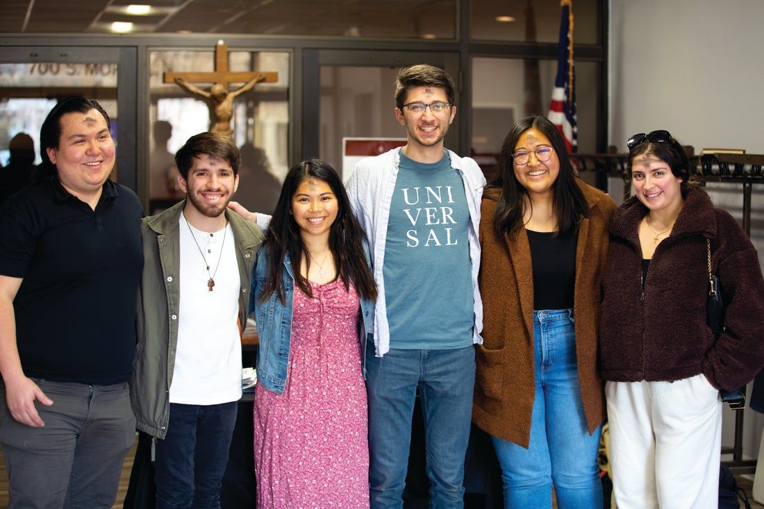 A group of people are posing for a picture in front of a cross.