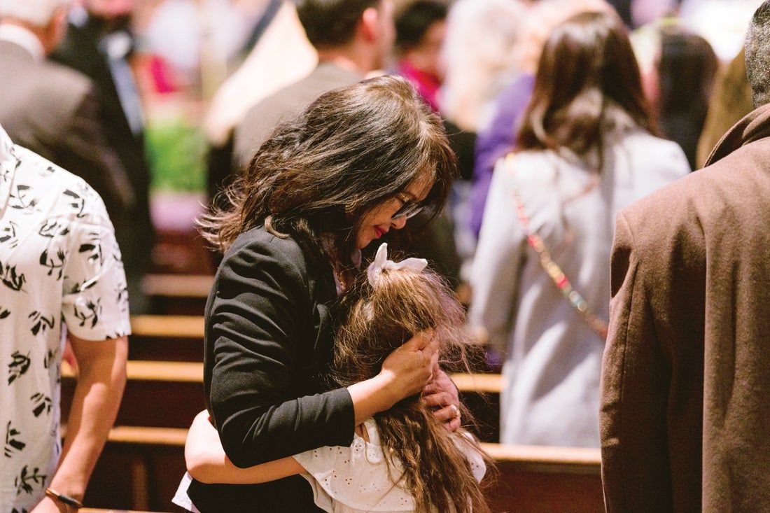A woman is holding a little girl in her arms in a church.