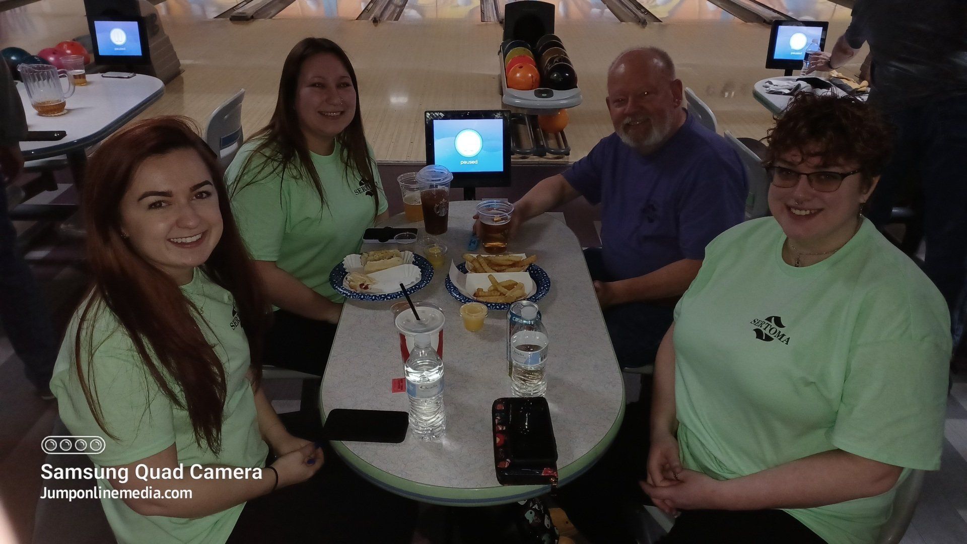 A group of people are sitting at a table in a bowling alley.